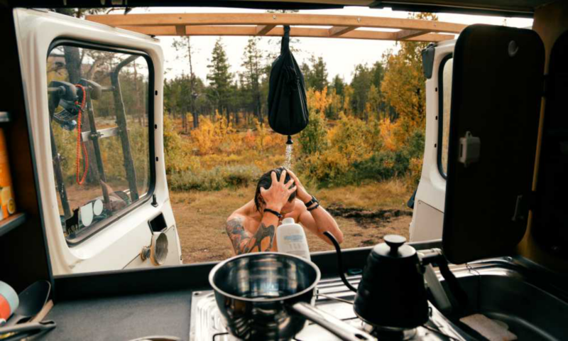 Hombre duchándose fuera de su Volkswagen California
