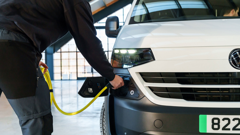 Front view of an electric VW e-Transporter van that is being charged