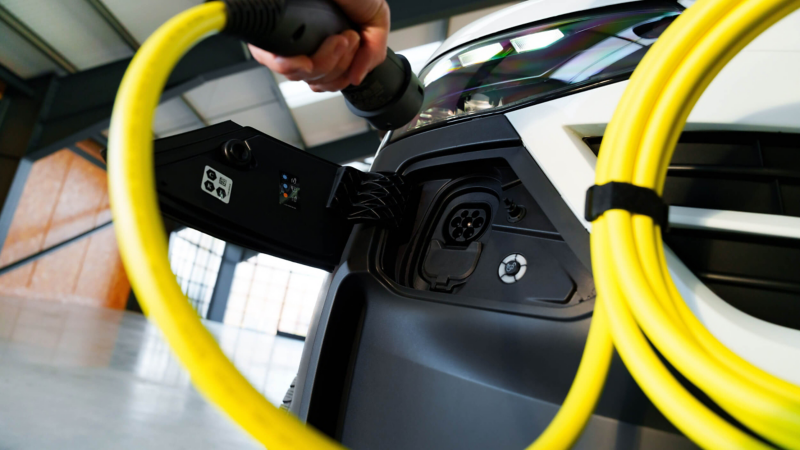 A person plugging a charging cable into a e-Transporter van