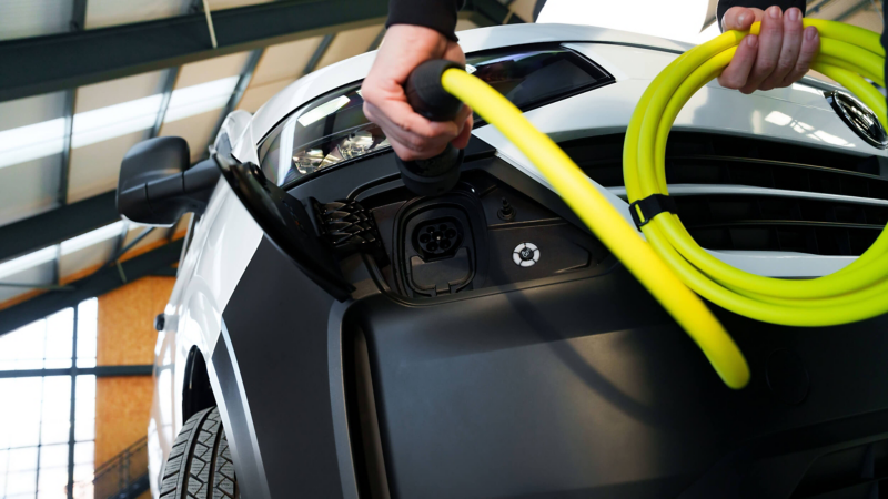 A person plugging a charging cable into the charging sucket of an e-Transporter Panel van