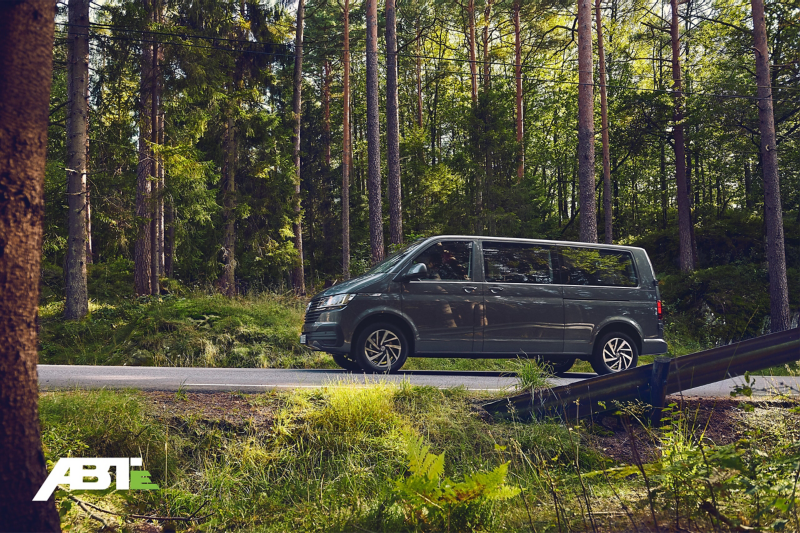 Une Volkswagen Caravelle traverse une forêt.