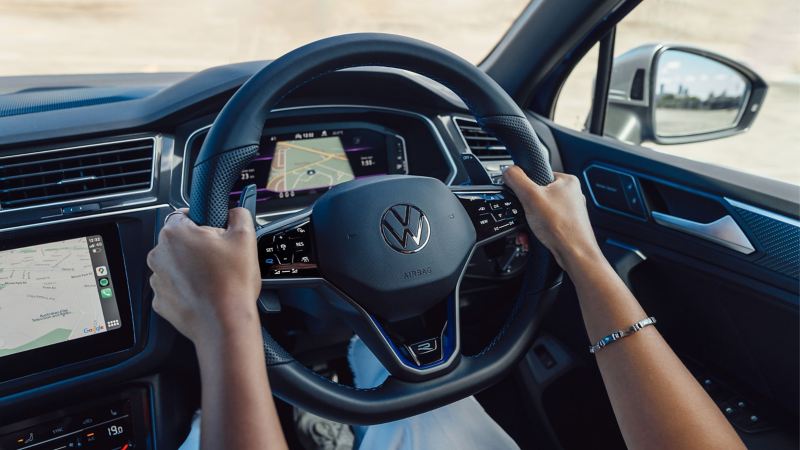 Woman in the driving seat of the Volkswagen Tiguan R holding the steering wheel In her hands