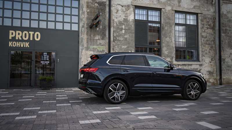 A VW Touareg R-Line drives across a road, view from the side.