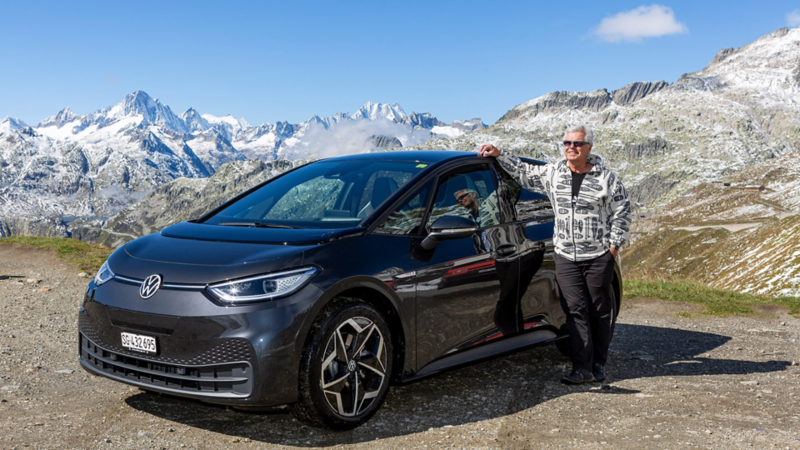 ID.3 seitlich von vorne und Felix Egolf lehnt sich an. Im Hintergrund die Alpen