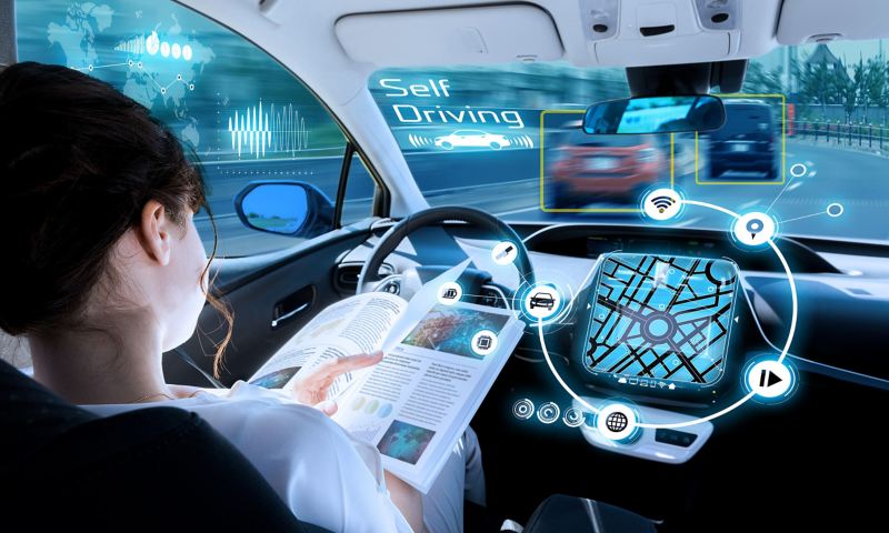 Foto-Grafik zeigt eine Frau, die eine Zeitschrift liest, während ihr Fahrzeug selbstständig mit seiner Umgebung kommuniziert und fährt.
