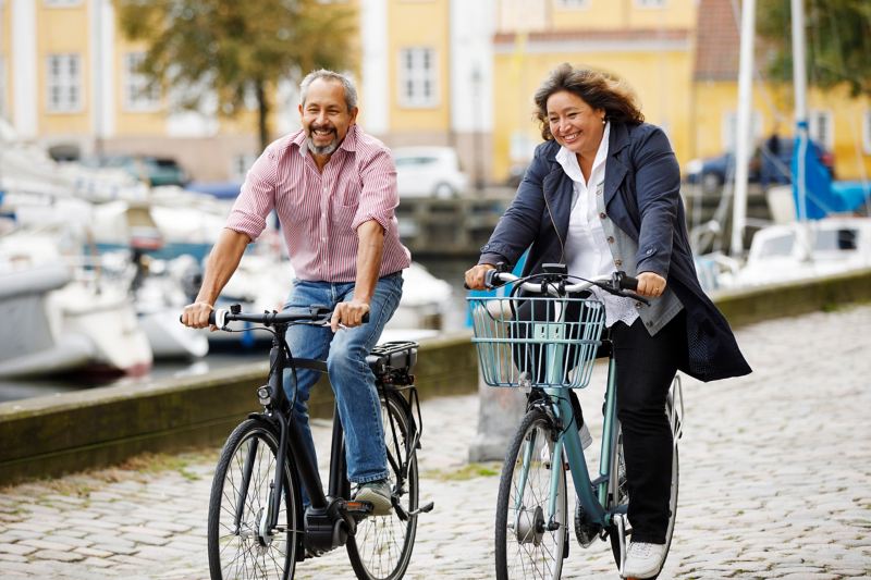 Eine Frau und ein Mann sind mit E-Bikes in der Stadt unterwegs.