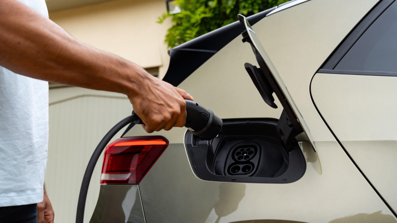 A person plugging their electric car in to charge