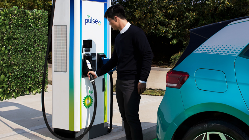 A man using a BP Pulse charger with an ID.3 parked next to the station