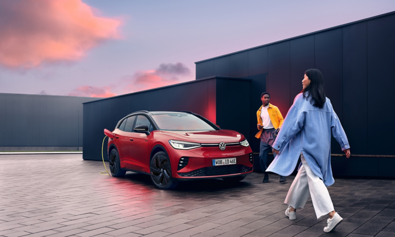 Two people approach a red ID.4 GTX at sunset