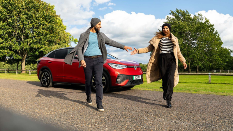 A couple walking passed a red ID.5 Style car