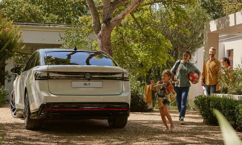 A VW ID.7 is parked in front of a house. rear view of the vehicle. 