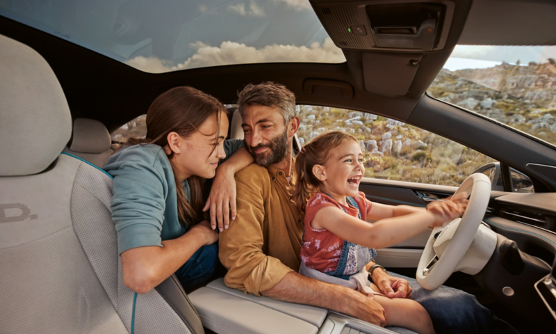 Two parents sitting with their young child in the front seats of a parked ID.7