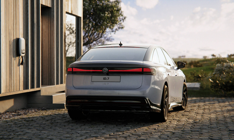 Back view of a VW ID.7 parked next to a wall with a wall-box charging device 