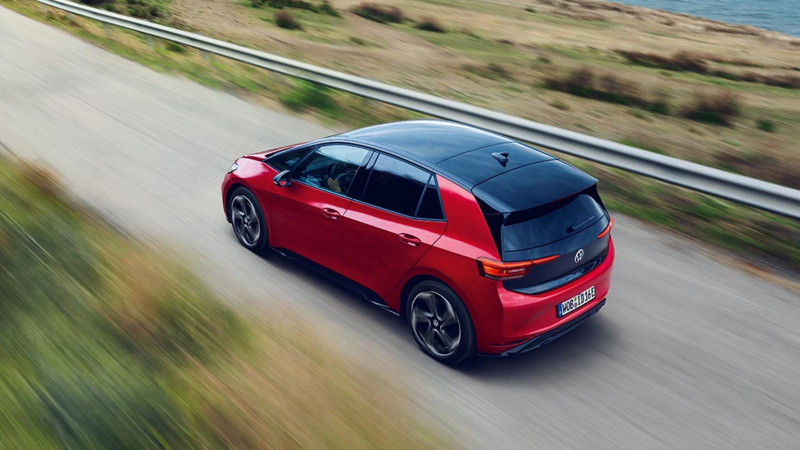 a red electric VW vehicle driving through the countryside