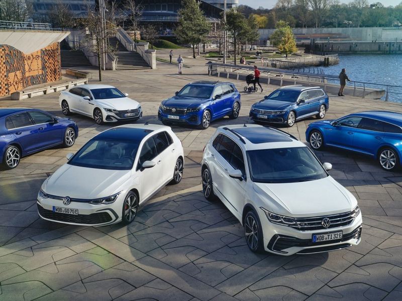 Top view of four blue and three white VW hybrid models on a sunny waterfront.