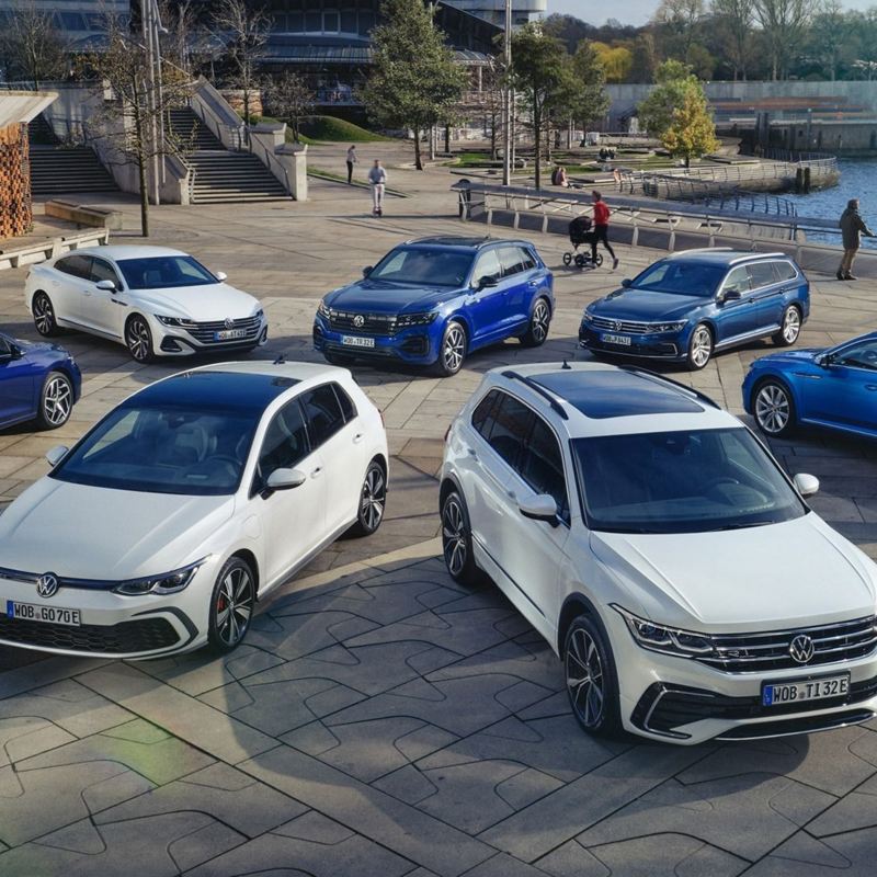 Top view of four blue and three white VW hybrid models on a sunny waterfront.