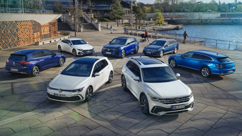 Top view of four blue and three white VW hybrid models on a sunny waterfront.