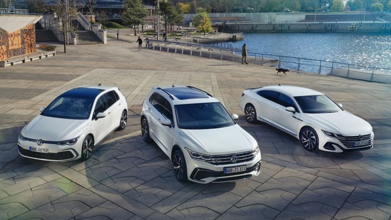 3 white VW hybrid models parked near a lake