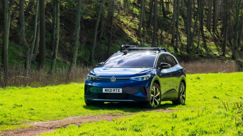 A dark blue Volkswagen ID.4 with roof bars attached parked in a field