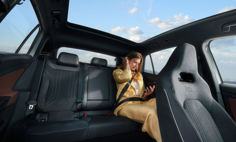 Interior view of a VW ID.5, front view of the back seat on which a person is sitting 