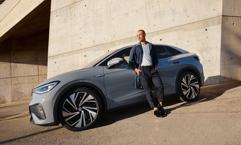 A person stands in at the side of a parked grey VW ID.5