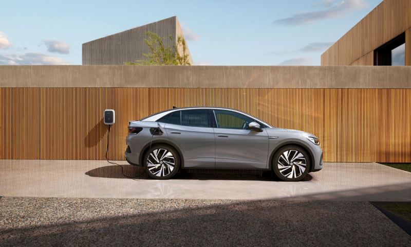 Side profile of a grey VW ID.5 charging against a fenced backdrop