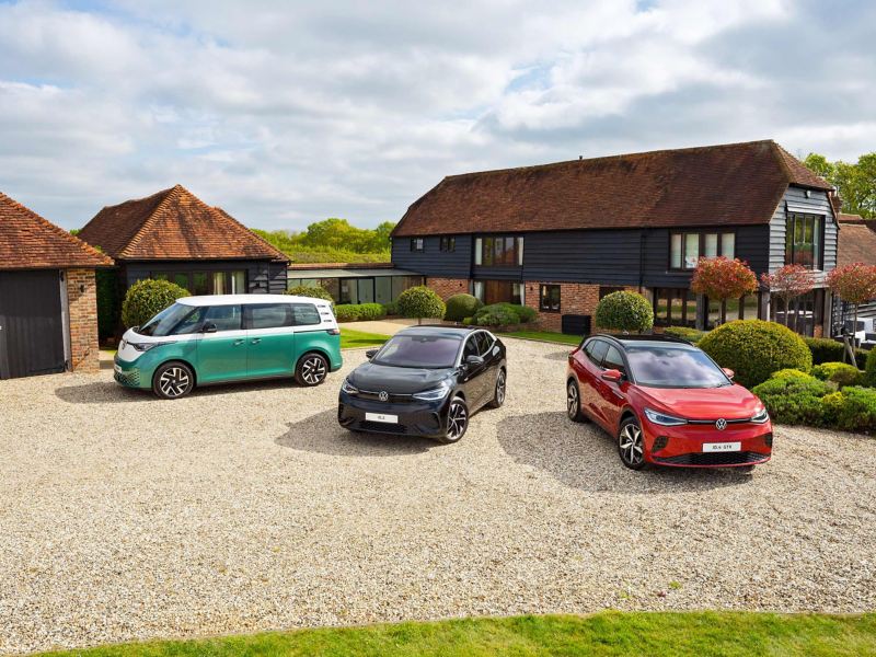 Photo showing a range of VW cars parked against a farmhouse backdrop. 