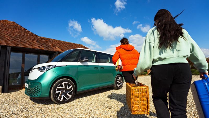 2 people approaching a parked ID Buzz ready to pack their picnic