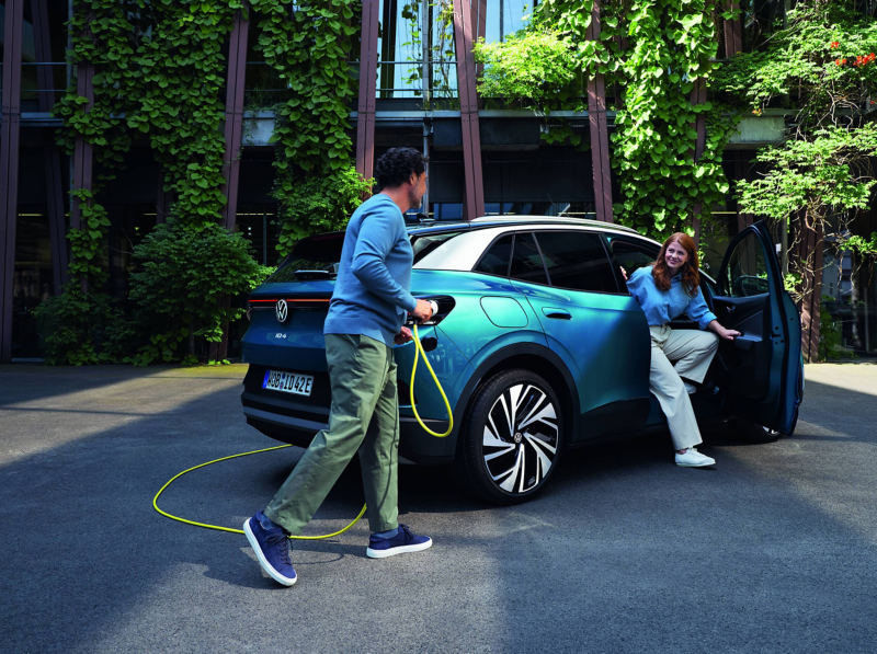 A man and woman beside an electric VW car