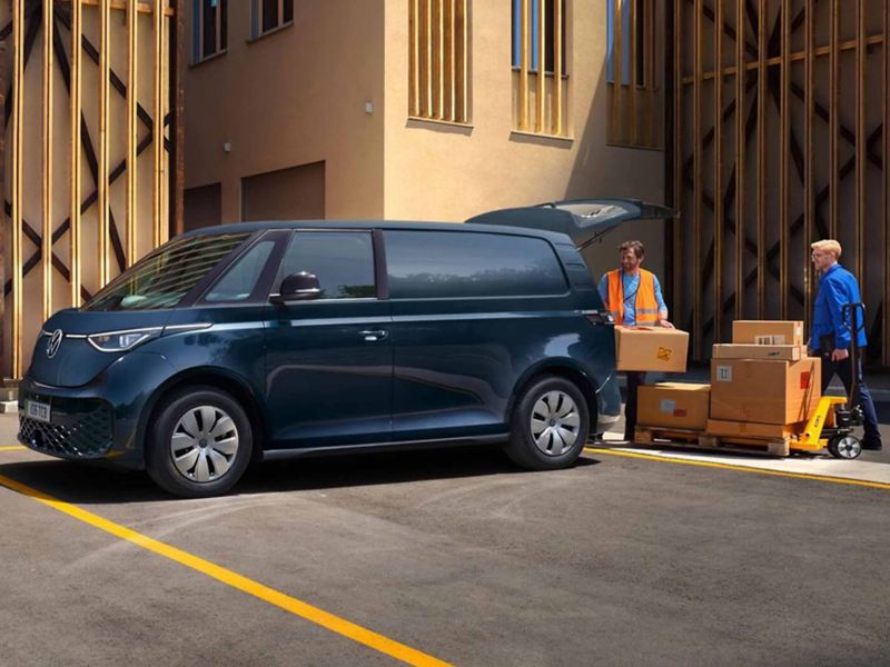 two people unload boxes from the boot of a navy blue ID. Buzz Cargo parked 