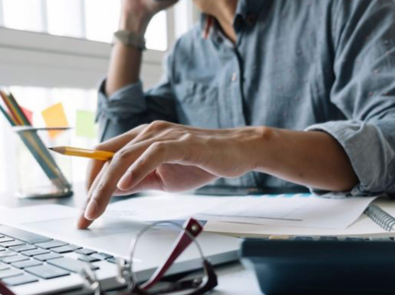 Person at desk using laptop to compare the costs