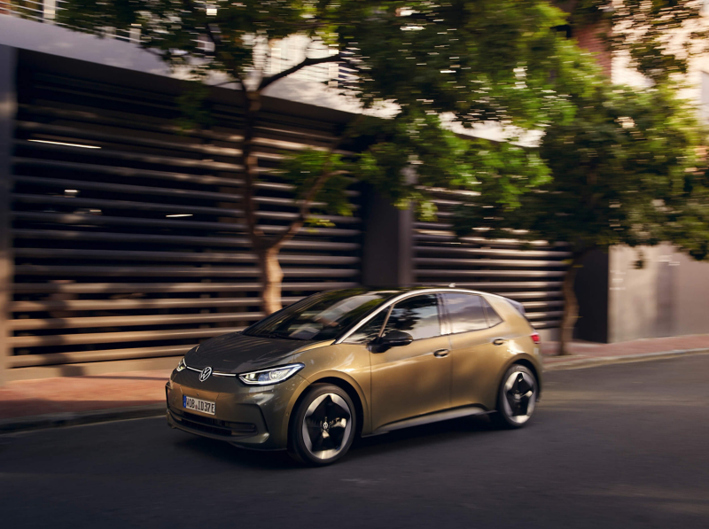 An electric VW driving along a tree-lined road