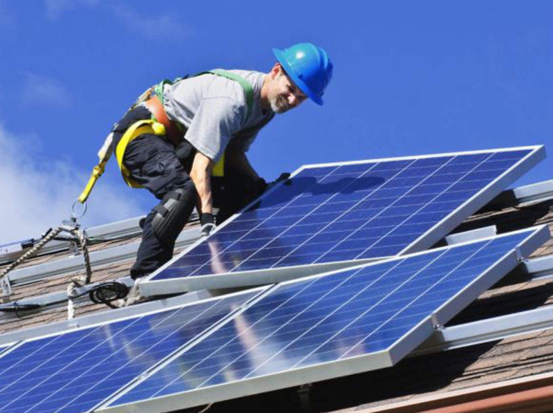 A man on a roof with solar panels