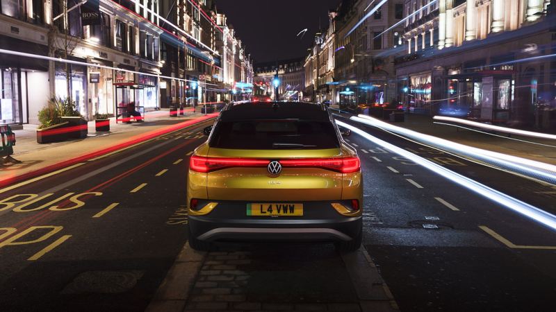 ID.4 parked in a high street at night taken with a slow shutter speed so you see a streak of car lights going past