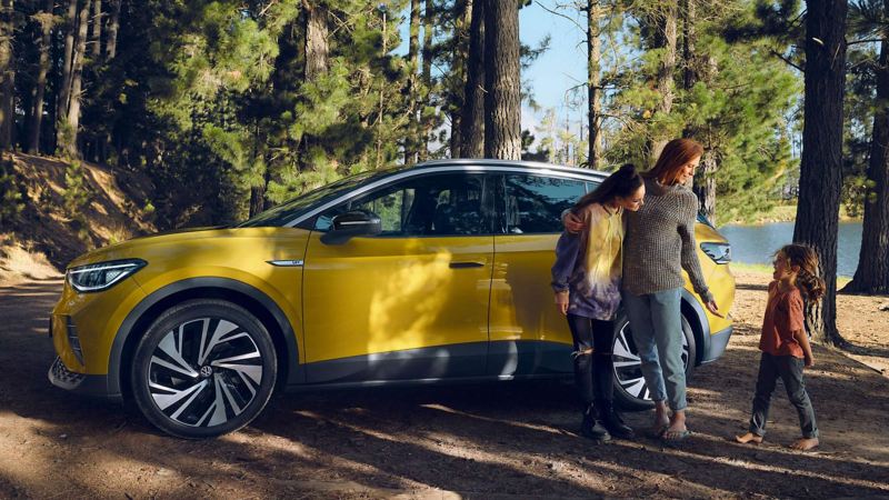 A family of 3 standing next to a VW ID.4