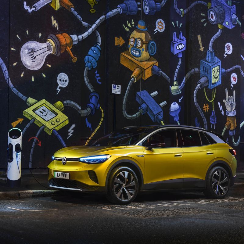 a yellow ID.4 parked outside a wall of graffiti 