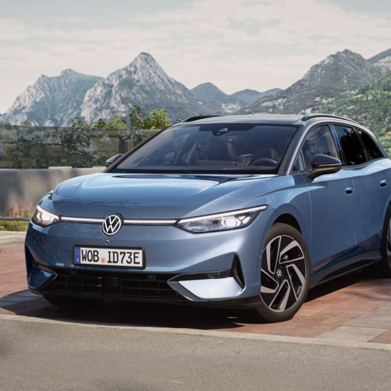 a new ID.7 Tourer parked by a lake with mountains in the background