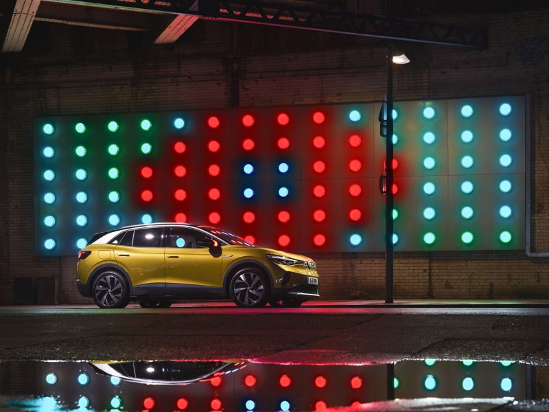 Exterior design of the Volkswagen ID. 4 parked next to a wall with a light display