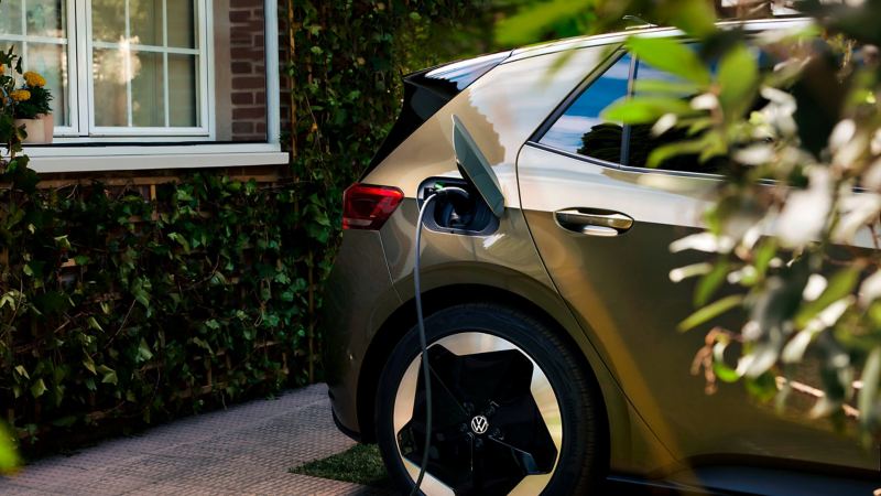 A view of a VW ID.3 parked in front of a garage and connected to a charging station.