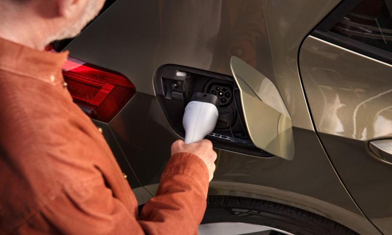 A man plugs a charging connector into the charging socket on the VW ID.3.