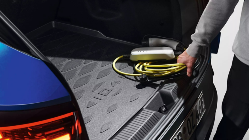 A lady about to plug an electric charging cable into her car