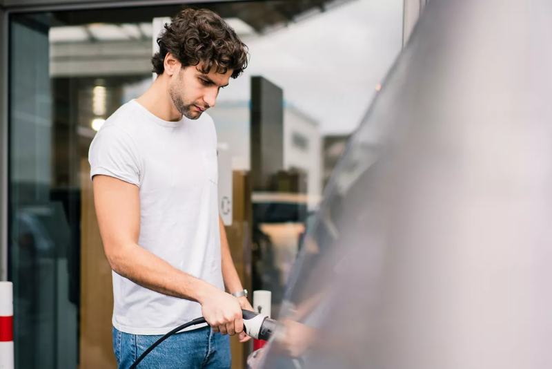 Man in a white tshirt charging car