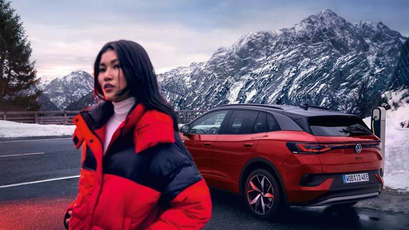 Woman beside a parked ID.4 with a snowy mountain background