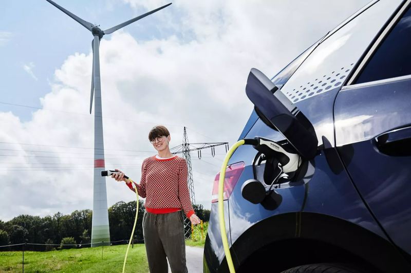 Woman holding a charger with wind turbine in background