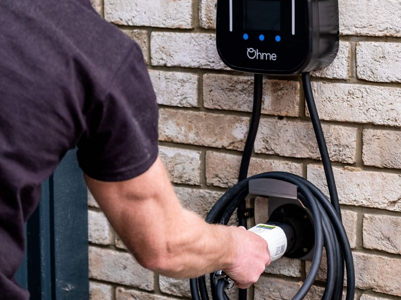 Photo showing a man connecting a charging cable to a wall charger. 