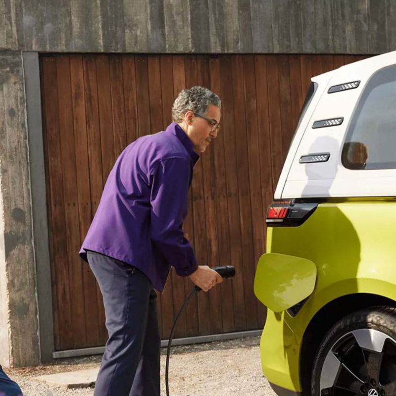 a man plugging a home charger into a yellow ID.Buzz