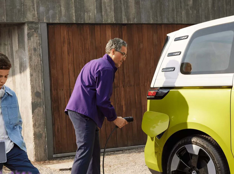 a man plugging a home charger into a yellow ID.Buzz