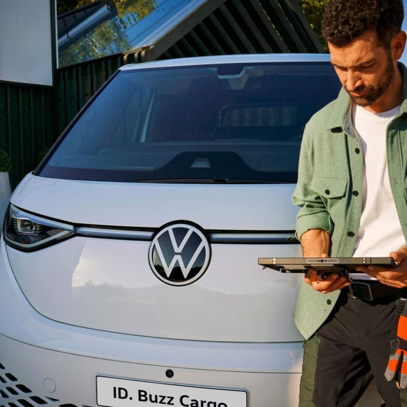 A man standing in front of VW ID. Buzz Cargo with tablet