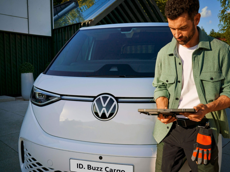 A man standing in front of VW ID. Buzz Cargo with tablet