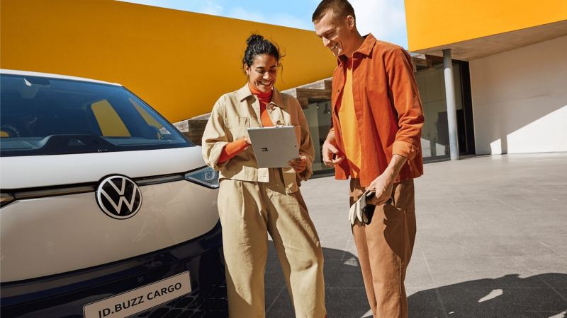 2 people stand in front of VW ID. Buzz Cargo with tablet